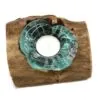 A tealight candle in a turquoise glass holder set on rustic natural wood.