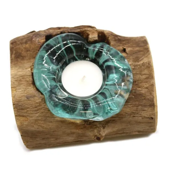 A tealight candle in a turquoise glass holder set on rustic natural wood.