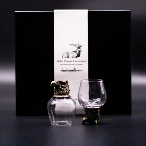 Wild Forest Creatures Bronze Glass Set - Eagle Design Black Box Two antique bronze and glass eagle-themed drinking glasses displayed before a black “Wild Forest Creatures” box.