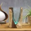Handcrafted aqua glass and natural wood decorative sculpture on a wooden table with plant decor.