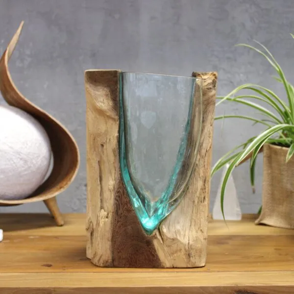 Handcrafted aqua glass and natural wood decorative sculpture on a wooden table with plant decor.
