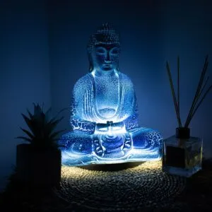 Blue Meditation Buddha Lamp. Illuminated blue Buddha statue on woven mat with succulent plant and glass reed diffuser