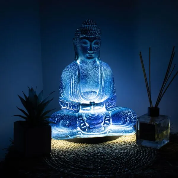 Blue Glass Buddha Statue - Illuminated Meditative Glow Blue Meditation Buddha Lamp. Illuminated blue Buddha statue on woven mat with succulent plant and glass reed diffuser