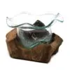 Hand-blown glass bowl with organic curves resting on a textured reclaimed wooden base.