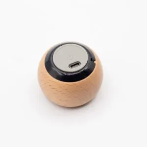 A small round wooden smart device with a grey power button and USB-C port on top.