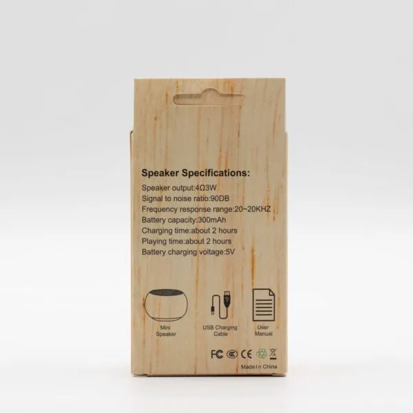 Back of a small wood‑grain cardboard box showing mini speaker specifications and included accessories.