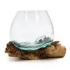 A handcrafted aqua-tinted glass bowl melted onto natural driftwood base for rustic home décor.