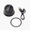 A black portable Bluetooth speaker with charging cable and rubber base ring on a white background.