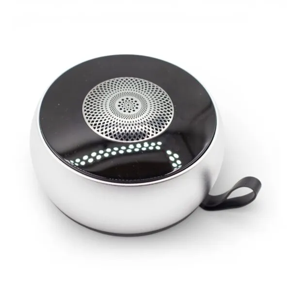 A compact silver and black circular Bluetooth speaker with a metallic grille and carrying loop.
