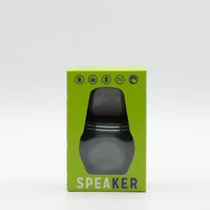A small cylindrical portable speaker in metallic grey inside a bright green retail packaging box.