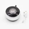 Compact black and white Bluetooth speaker with metal design and USB charging cable on white background.