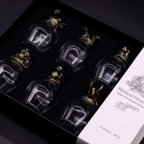 Luxury bronze creature glass set in black box with ornate mythical designs.