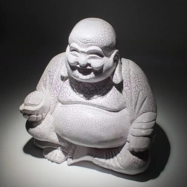 A crackled pale Laughing Buddha statue smiling peacefully under soft directional light.