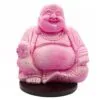 Bright pink Laughing Buddha statue with cracked texture sitting cross-legged on a dark brown base.