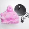 Pink laughing Buddha statue beside a black lamp base with cord on a white background.