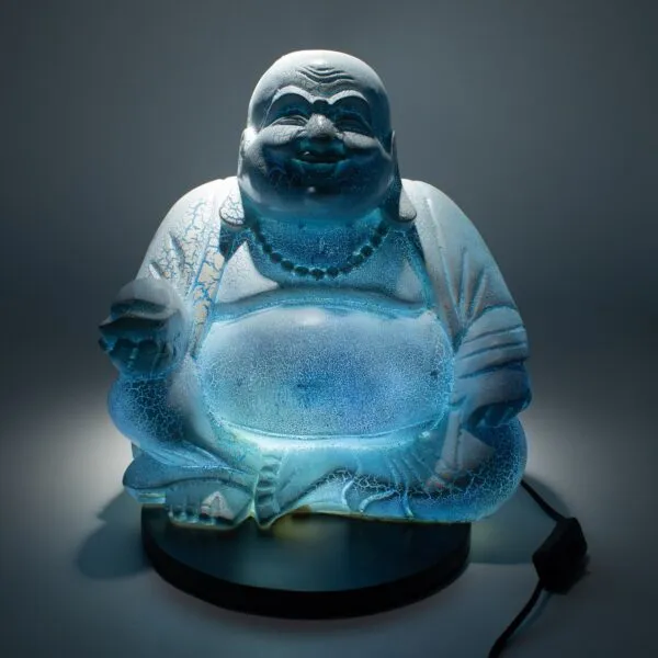Alternative Birthday Gifts Glowing blue Laughing Buddha statue with crackled glass texture on a black base in darkness.