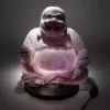 A glowing lilac Laughing Buddha lamp with a cracked glass texture on a black base.