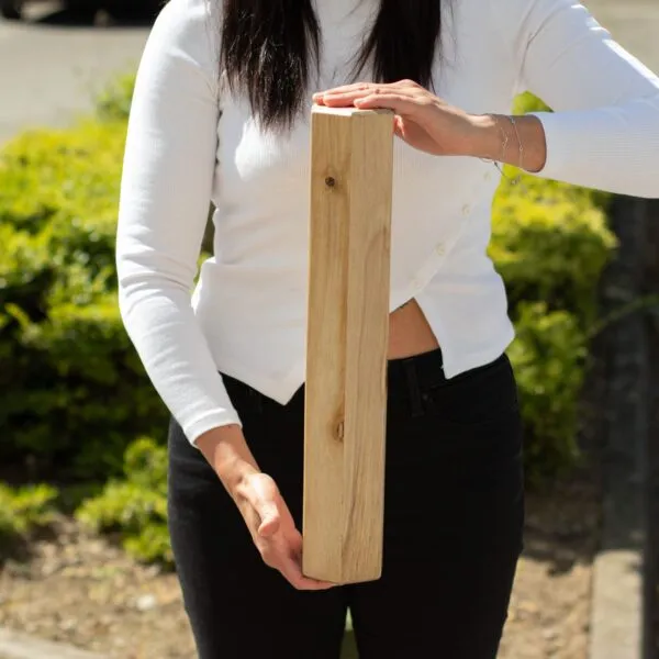 Wooden Craft Block Solid Timber Light Natural Visible Grain A woman holding a rectangular, light-coloured wooden block vertically outdoors.