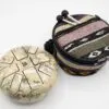 Steel tongue drum with an antique world map print, a colourful woven bag, and mallets.