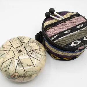 Steel tongue drum with an antique world map print, a colourful woven bag, and mallets.
