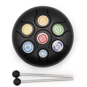 A black steel tongue drum with colourful chakra symbols and two mallets.