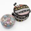 A patterned steel tongue drum and bohemian carrying bag with mallets on a white background.