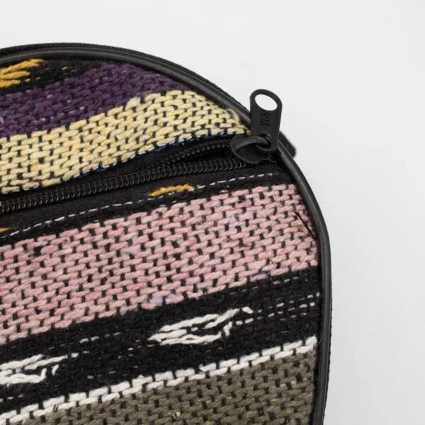 Close-up of a circular colourful striped woven fabric case with a black zipper.
