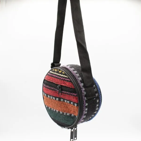 Small round hand-woven bag with colourful geometric patterns hanging against a white background.