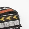 Close-up of a patterned woven bag featuring a black zip pull marked TONI.