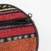 Close-up of a colourful, striped woven circular pouch with a black zip.