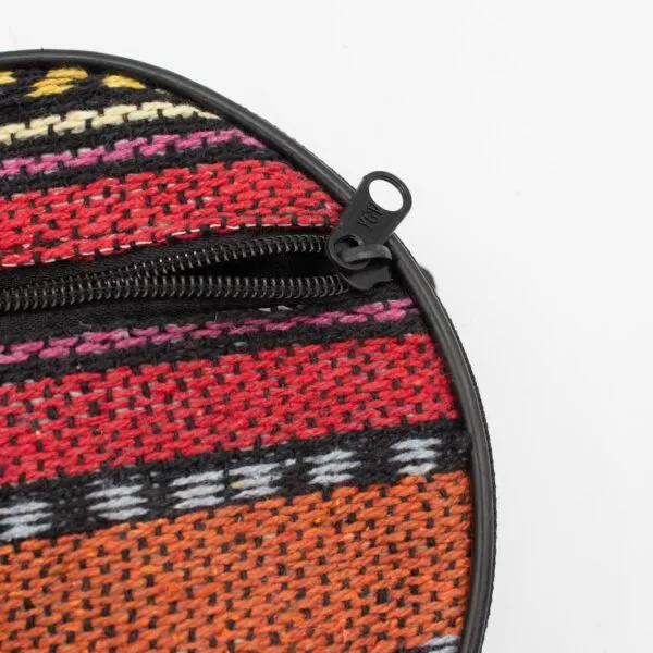 Close-up of a colourful, striped woven circular pouch with a black zip.