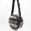 A colourful round patterned woven bag with a vertical zip and black strap.