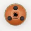 Underside of a reddish-brown Chakra drum featuring a colourful patterned rim and rubber pads.