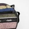 Close-up of a round, multicoloured woven fabric bag with a black zipper.