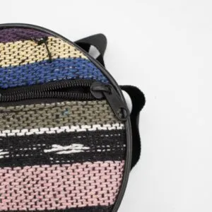 Close-up of a round, multicoloured woven fabric bag with a black zipper.