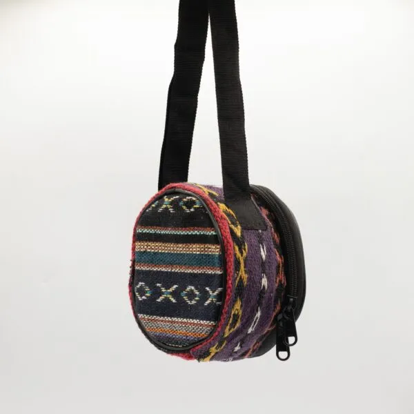 Colourful round patterned fabric bag with a black strap against a white background.