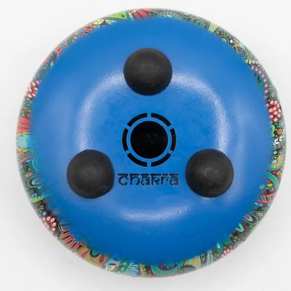 Colourful, hand-painted bottom of a round percussion instrument with black rubber feet.
