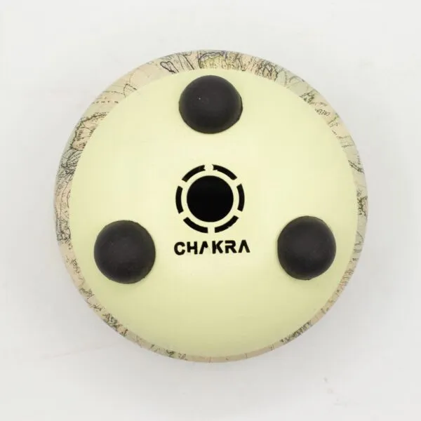 Bottom of an off-white steel tongue drum with rubber feet and Chakra text.