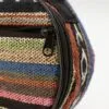 Close-up of a colourful striped woven textile case with a YONI zipper pull.
