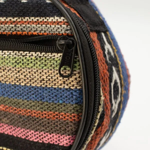 Close-up of a colourful striped woven textile case with a YONI zipper pull.