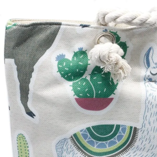 Beige canvas tote bag featuring an embroidered llama and cactus pattern with rope handles.