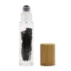 Clear glass roller bottle filled with black gemstones beside a natural wooden cap.