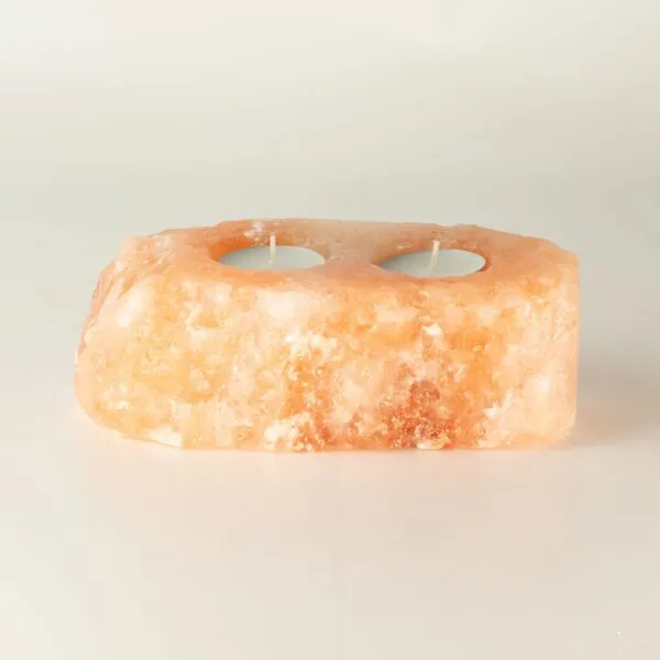 Hand-carved pink Himalayan rock salt double tea light candle holder with two candles.