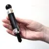 Hand holding a black obsidian obelisk wand with silver accents and orange stones.