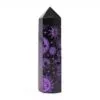 Six-sided black stone obelisk point carved with sparkly purple celestial symbols.