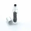 Clear glass gemstone roller bottle filled with black stone chips and a silver cap.