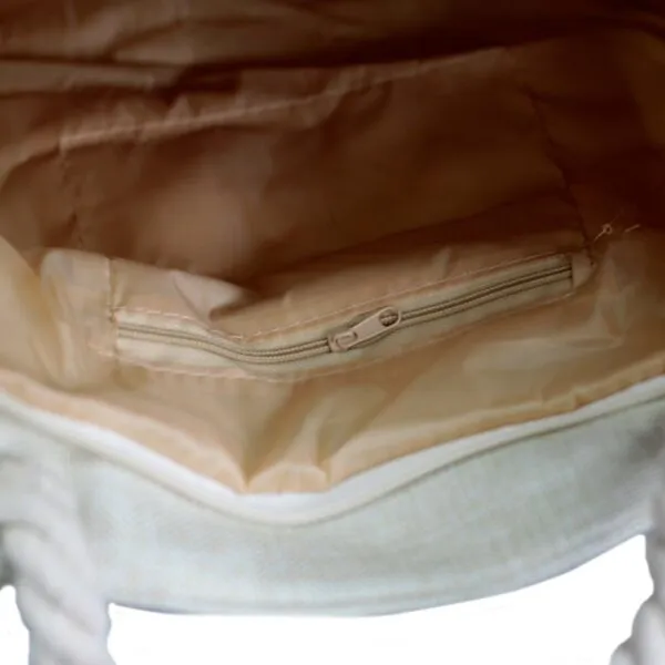 Interior of a natural canvas tote bag with a peach lining and zipped pocket.