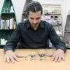 A man looking down at three clear optical glass crystal balls on stands.