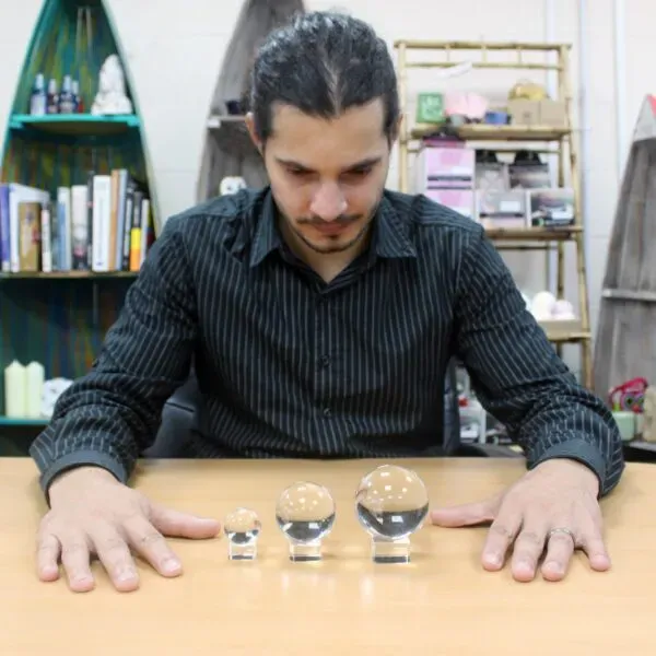 A man looking down at three clear optical glass crystal balls on stands.