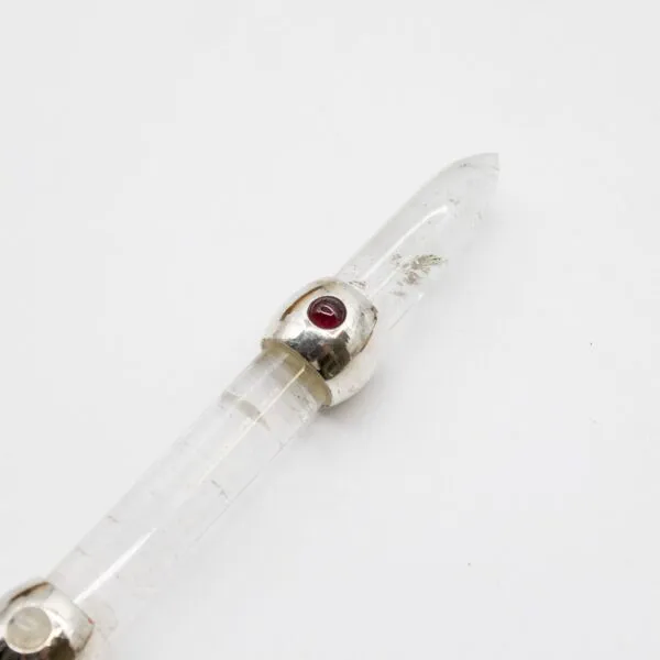 Clear quartz crystal wand featuring a sterling silver band set with a red cabochon gemstone.